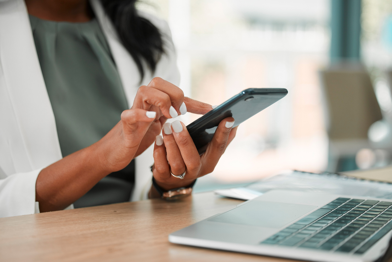 Woman typing on phone in front of computer, Google Workspace