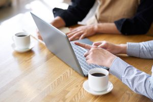 Two business professionals discussing AI business visibility and digital marketing strategy while reviewing information on a laptop.