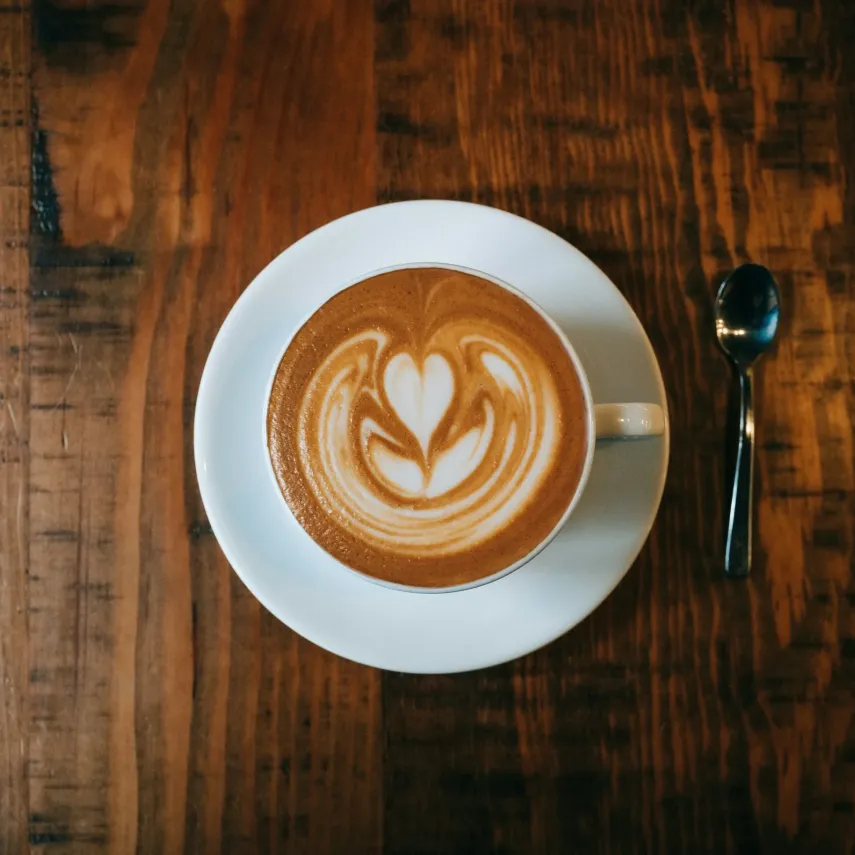 A decorative "flat white", an Aussie style cappuccino, on a dark wooden table.